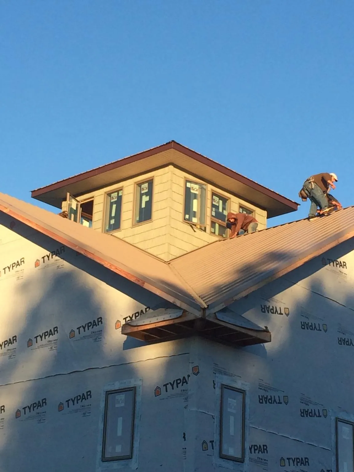 Roofers working around a rooftop cupola on a new metal roof at sunset — Roof Waterproofing in Oak Hill by Roofing Brothers